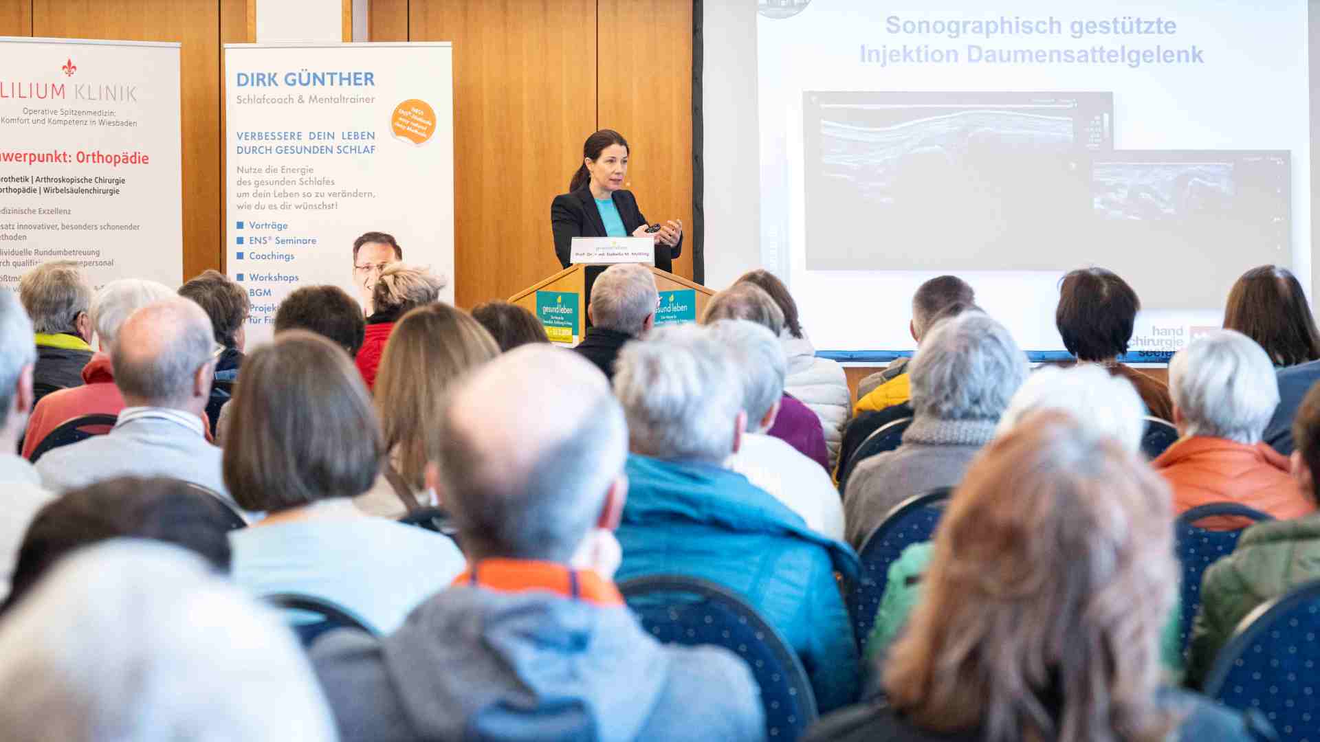 gesund_leben_messe_Vortragsprogramm Besucher und Besucherinnen im Vortragsraum hören interessiert einer Referentin zu.